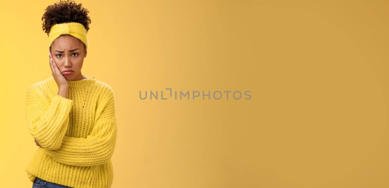 Upset cute gloomy young timid girl offended feel sadness regret touch cheek painful toothache make upset miserable pitty expression, troubled uncertain what do standing insecure yellow background by Benzoix