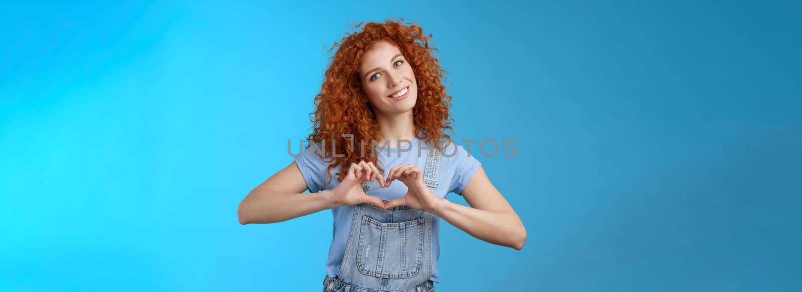 Caring tender lovely redhead girlfriend express sympathy tenderness gentle sympathy tilt head smiling broadly show heart love gesture chest cherish passionate romantic feelings, blue background by Benzoix