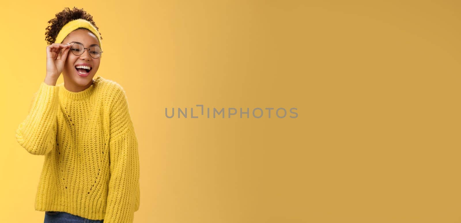 Charismatic stylish confident beautiful african-american joyful teenage girl touching glasses nose laughing broadly look down right corner grinning have fun joking enjoying, yellow background by Benzoix