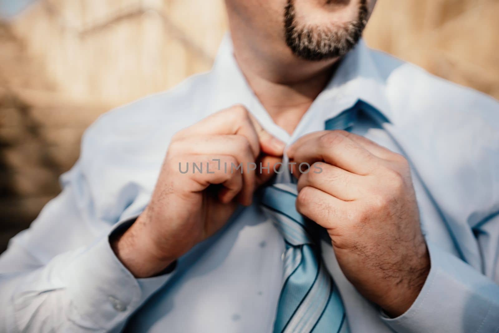 Close up of Man Adjusting Tie of Suit. Businessman in white shirt straightens his tie, close-up.