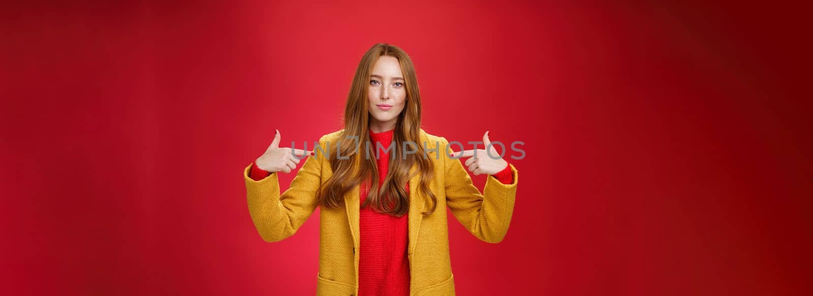 Self-assured assertive and optimsitic charming female entrepreneur with ginger hair in yellow coat pointing at herself proudly brag own success or willing to be candidate smiling confident by Benzoix