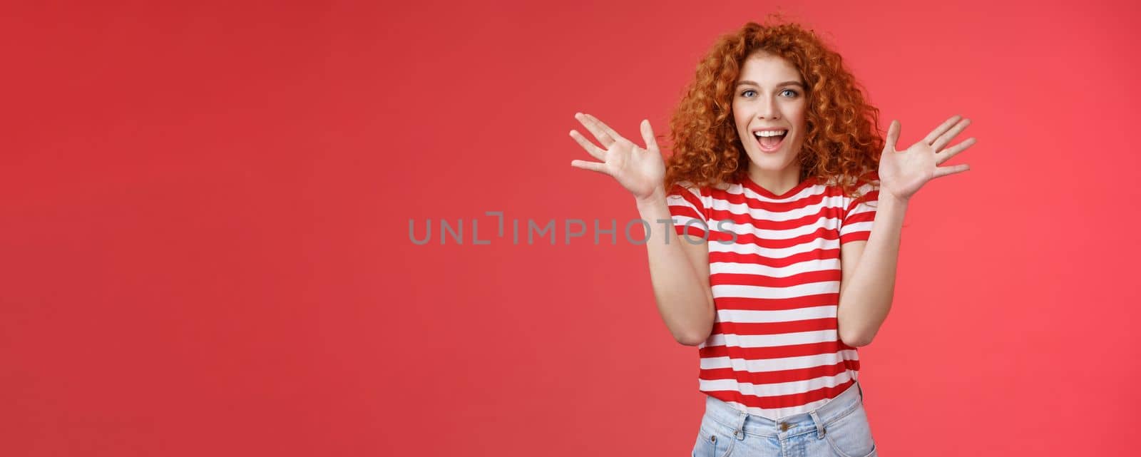 Awesome incredible performance bravo. Attractive cheerful cute european redhead curly female raise hands thrilled express excitement happiness joy look camera entertained delighted red background by Benzoix