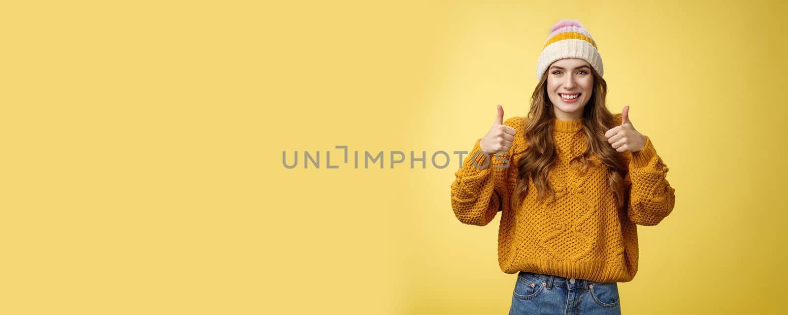 Supportive attractive 20s girl likes your idea show thumbs up positive reply affirmative answer standing pleased smiling recommending promotion satisfied give approval, agree yellow background.