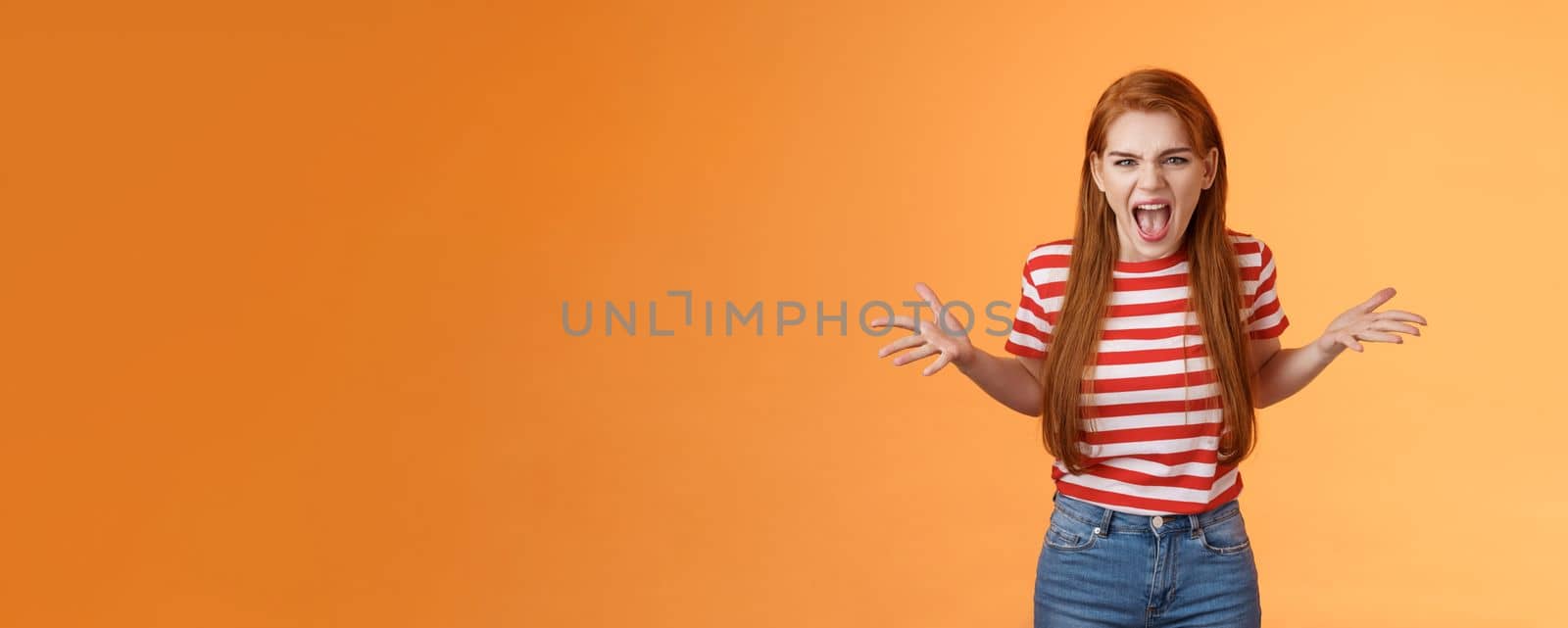 Pissed angry and annoyed redhead female arguing yelling with hatred and anger, spread hands sideways dismay, complain look disappointed upset and hateful, stand orange background. Copy space