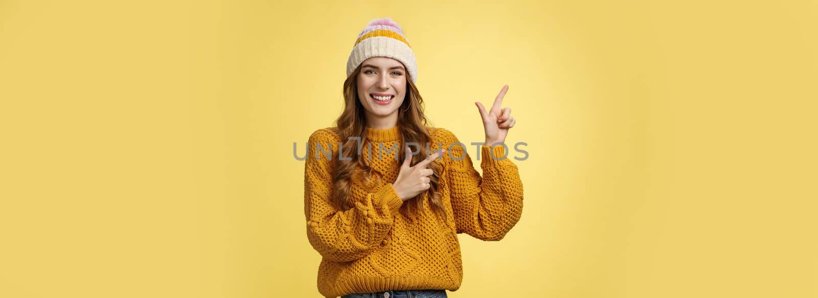 Charming carefree smiling young 20s woman wearing hat sweater pointing upper left corner sideways sharing interesting link awesome promotion delighted recommend cool product, yellow background by Benzoix