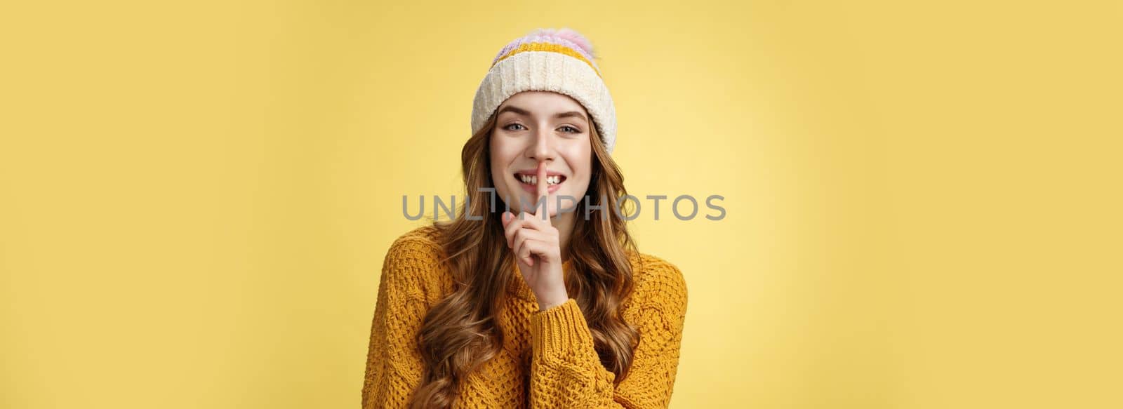 Shush listen. Portrait attractive flirty smiling devious cute european woman have secret showing shh gesture index finger pressed lips sharing interesting rumor, standing happily yellow background.