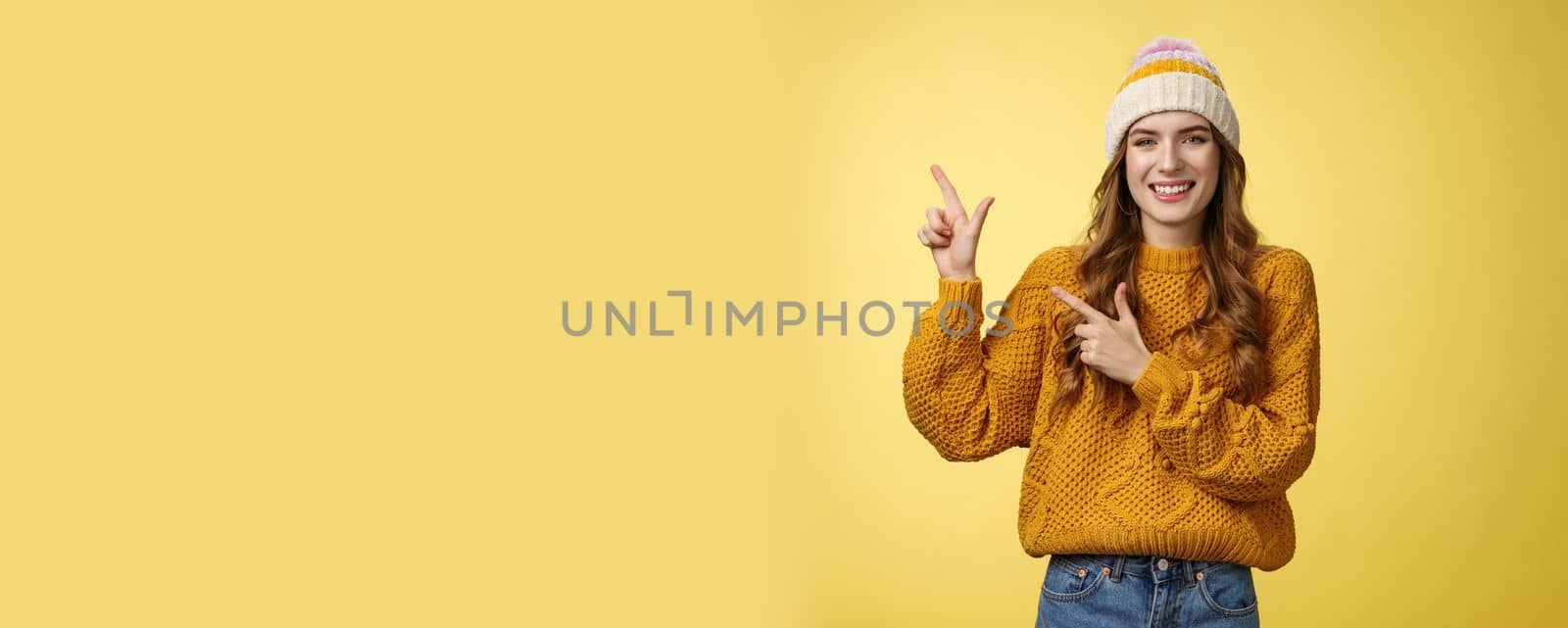 Charming carefree smiling young 20s woman wearing hat sweater pointing upper left corner sideways sharing interesting link awesome promotion delighted recommend cool product, yellow background by Benzoix