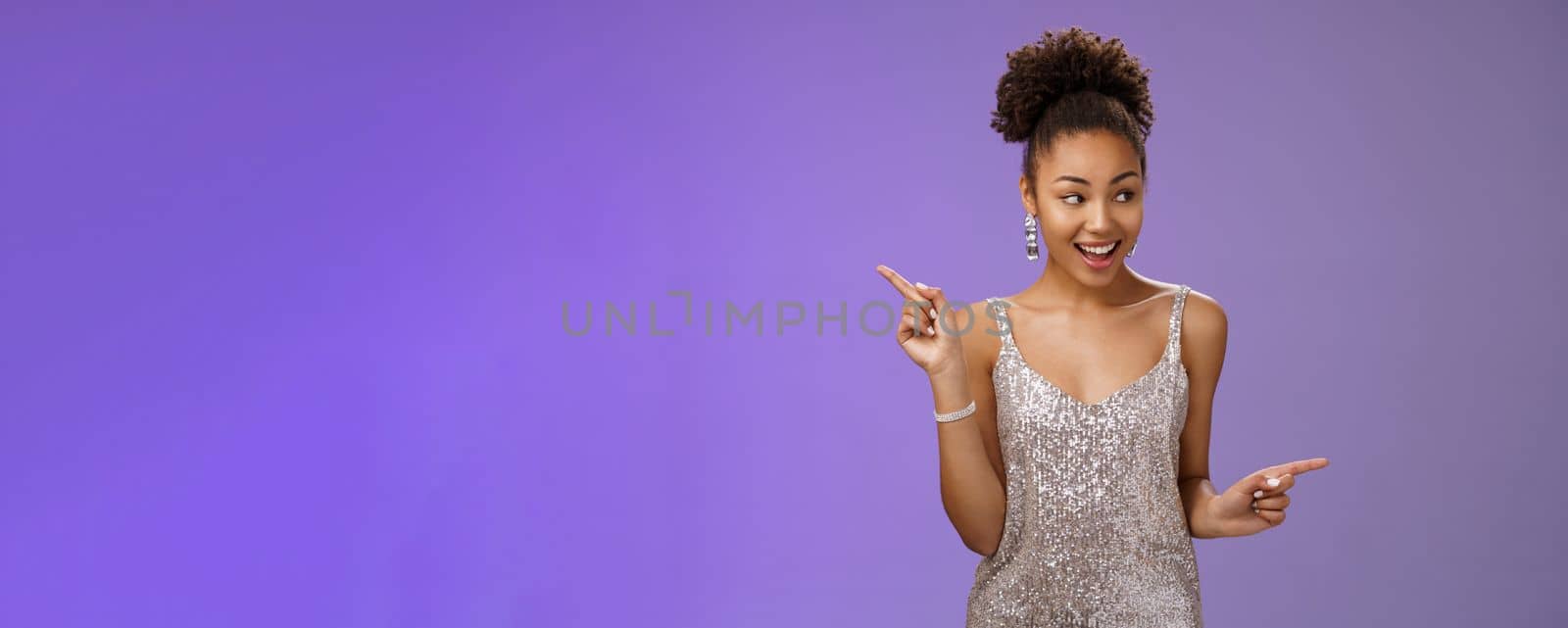 Good-looking excited glamour african-american. female student attend luxurious event in silver shiny perfect dress dancing look around pointing right left smiling pleased variants make choice.