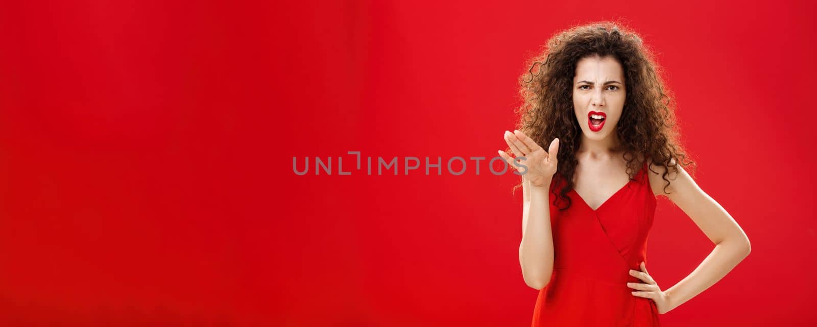 Girl chowing her temper to employees being fed up with unappropriate behaviour complaining standing pissed and dissatisfied gesturing with palm and holding hand on hip over red background by Benzoix