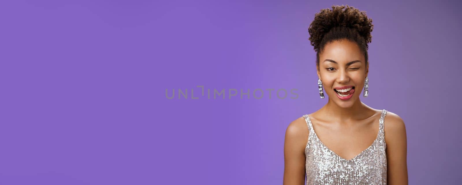 Close-up attractive african-american woman. in silver trendy evening dress earrings winking happily show tongue sassy gladly enjoying awesome disco party dancing foolind around have fun.