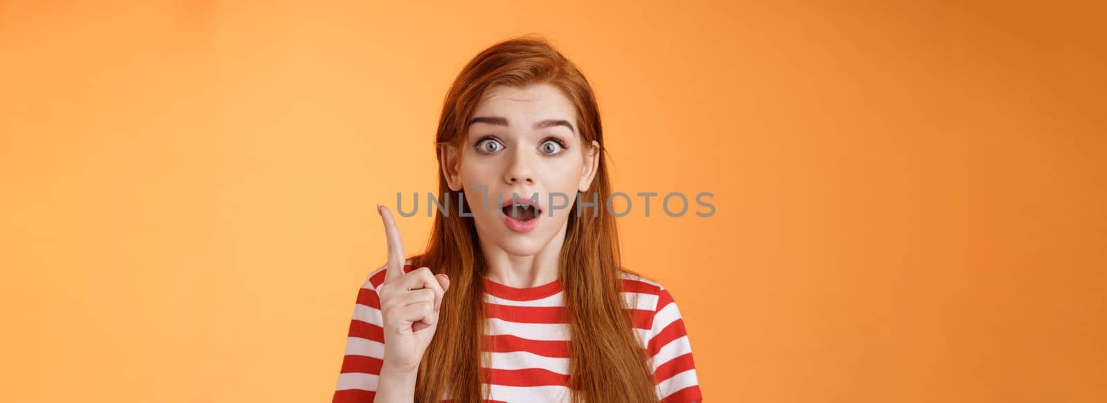Got idea. Excited redhead woman sharing interesting plan, raise index finger eureka gesture, open mouth say thought, remember important thing, stare camera stunned, finally understand.