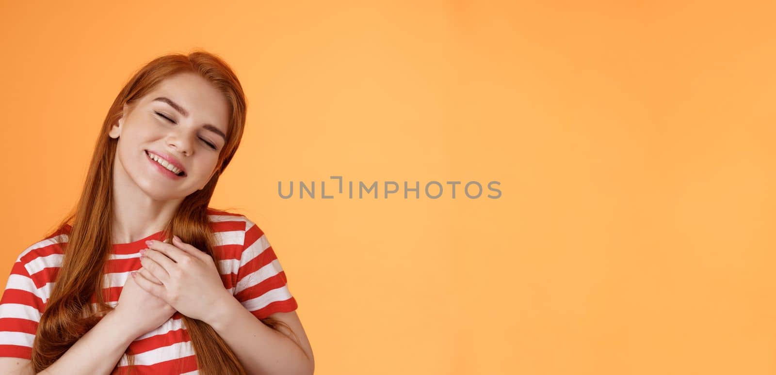 Close-up lovely caring tender redhead girlfriend feel love, close eyes smiling toothy silly grin, press palms heart, feel touched, daydreaming, have feelings, confess sympathy tasty food by Benzoix