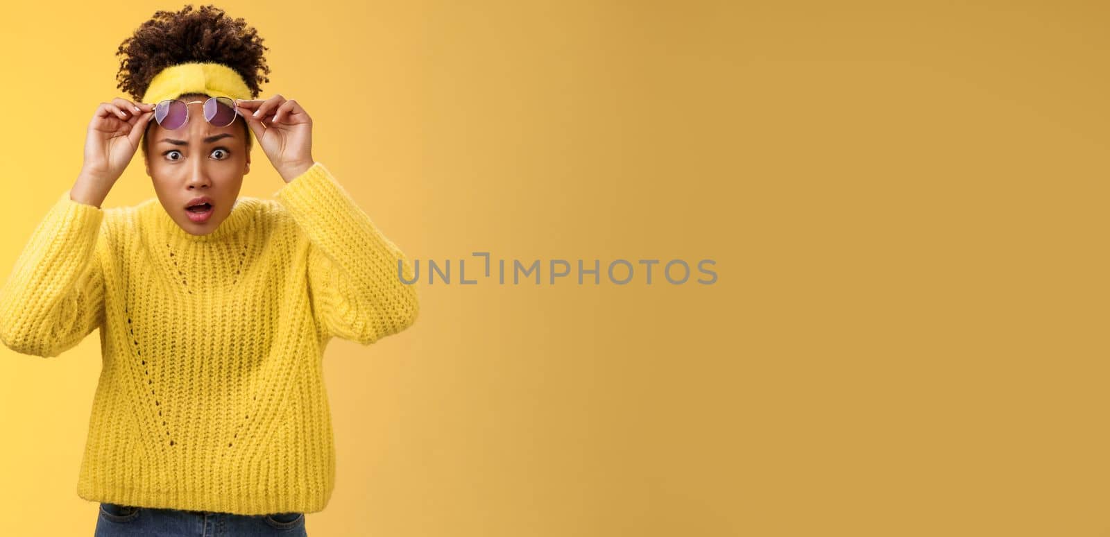 What heck. Shocked stunned confused african-american stylish modern girl in sweater headband take-off sunglasses widen eyes surprise speechless gasping look questioned freak-out, yellow background by Benzoix