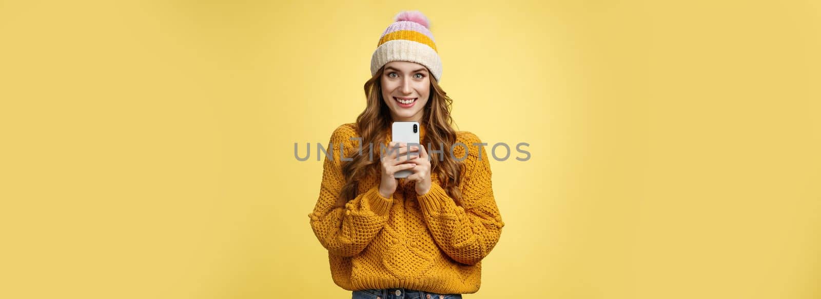 Smiling friendly-looking charming young trendy girlfriend holding brand new smartphone satisfied smiling upbeat receiving mobile phone birthday present grinning satisfied, taking photo you.