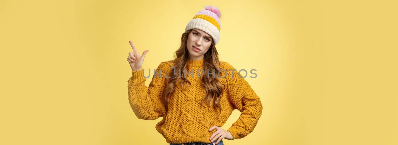 You call it advertisement, bad. Unimpressed displeased snobbish demanding female displeased hotel service pointing upper right corner cringing bothered frowning complaining yellow background by Benzoix