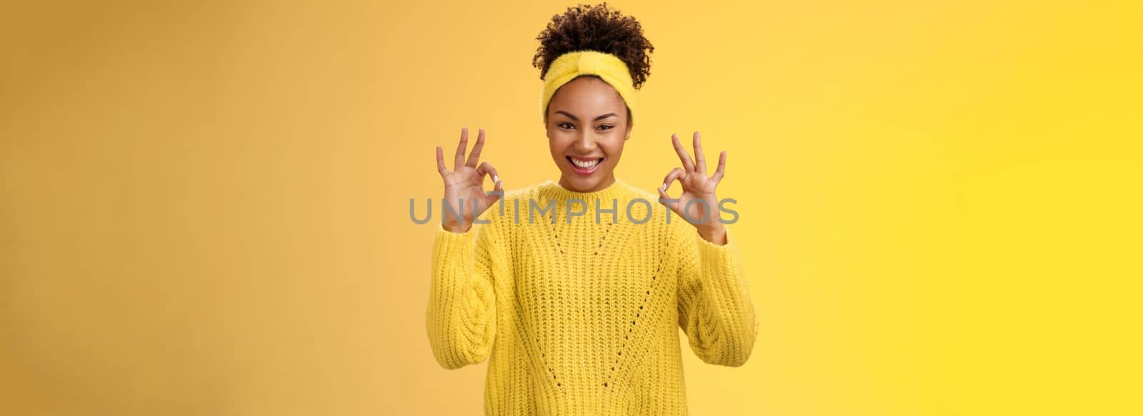 Count it done. Assured confident african-american woman in sweater headband show okay ok no worries gesture smiling self-assured plan goes fine, pleased good results, cheering yellow background.