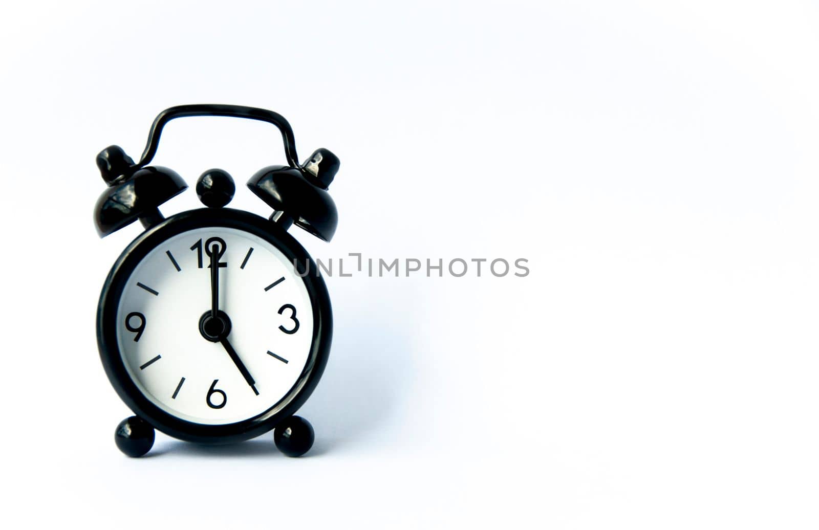 Black alarm clock pointing at 5 o'clock with customizable space for text on white background. Copy space.