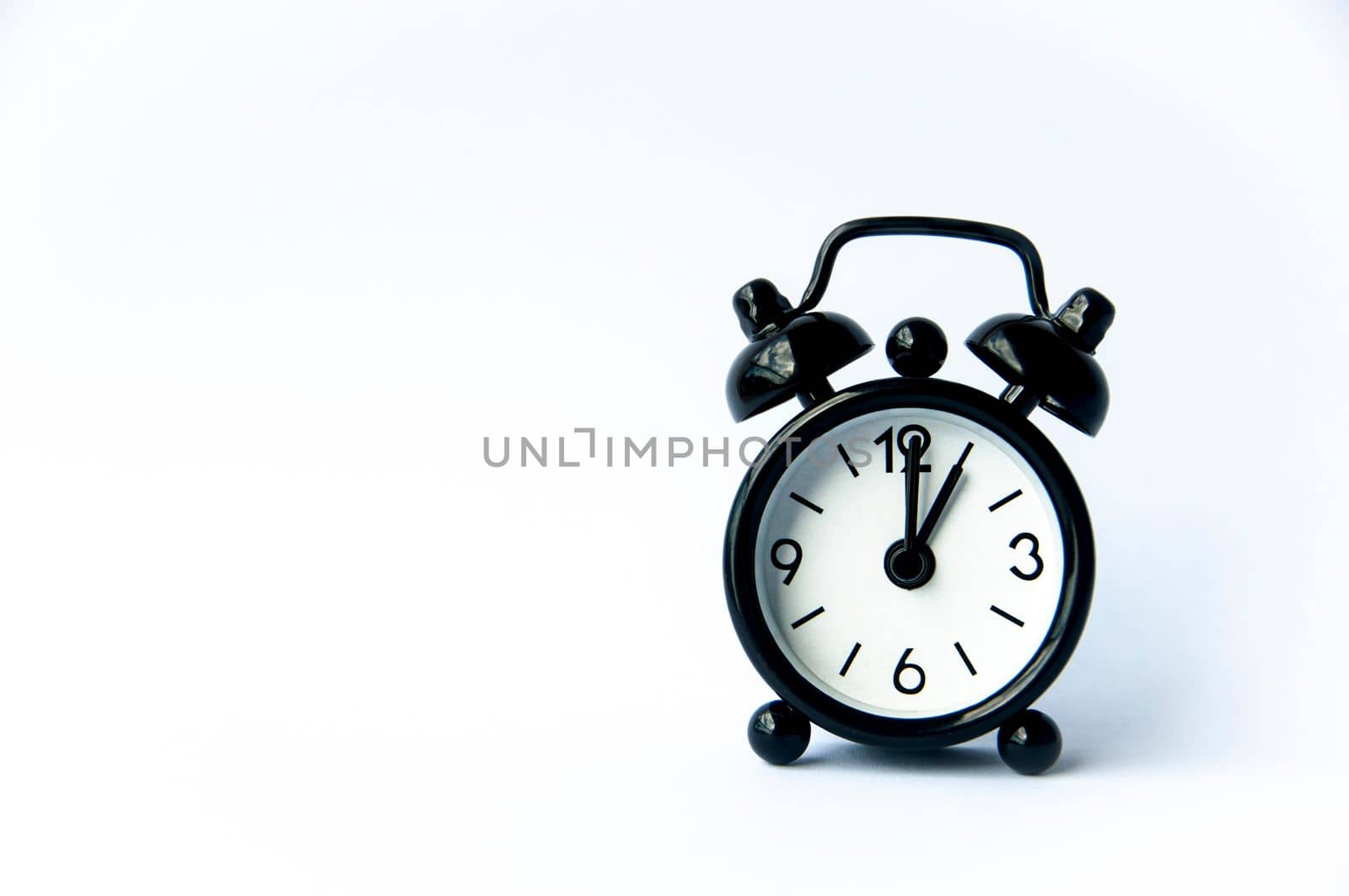 Black alarm clock pointing at 1 o'clock with customizable space for text on white background. Copy space.