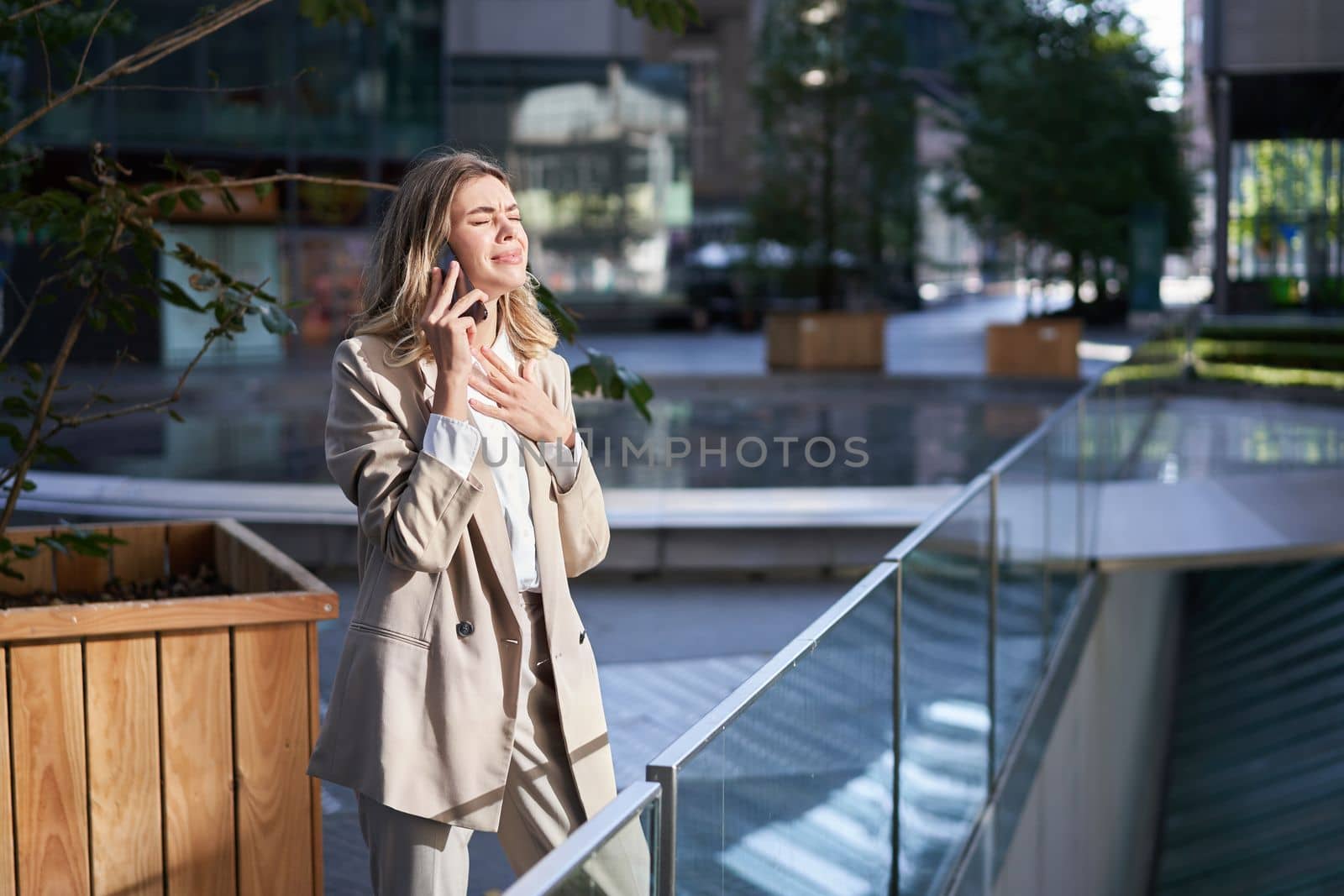 Frustrated corporate woman standing on street and having a difficult phone call, hear bad news on telephone conversation.