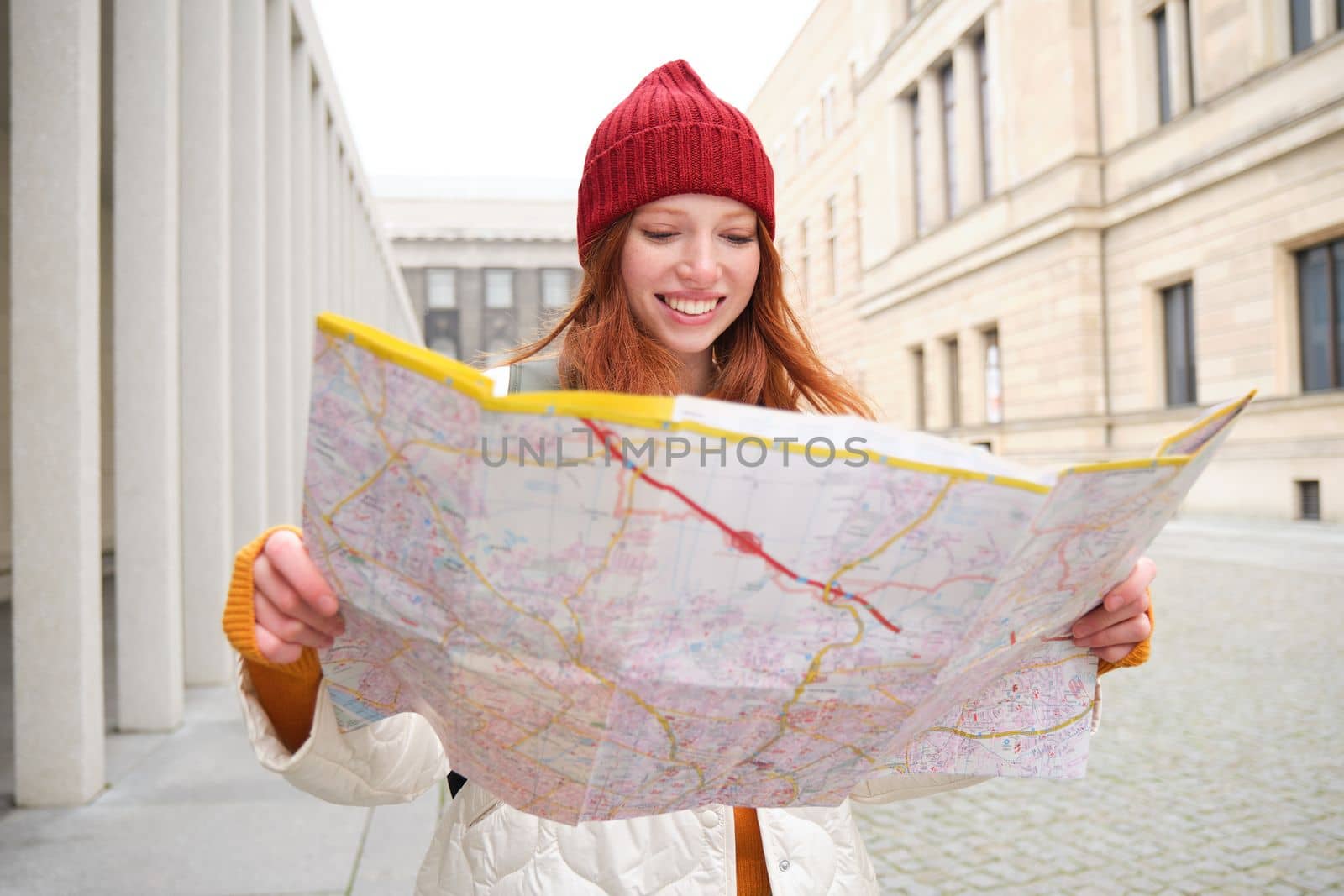 Redhead girl, tourist explores city, looks at paper map to find way for historical landmarks, woman on her trip around euope searches for sightseeing.