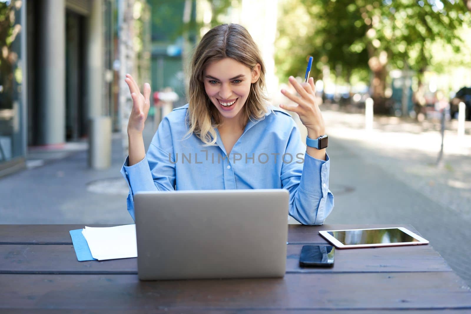 Young businesswoman, attend online video conference, writing down, working, taking notes in her documents, sitting outside on fresh air by Benzoix