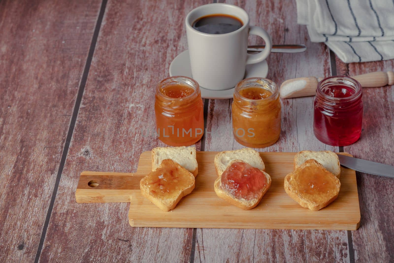 small pieces of toast with jam and coffee on a wooden table