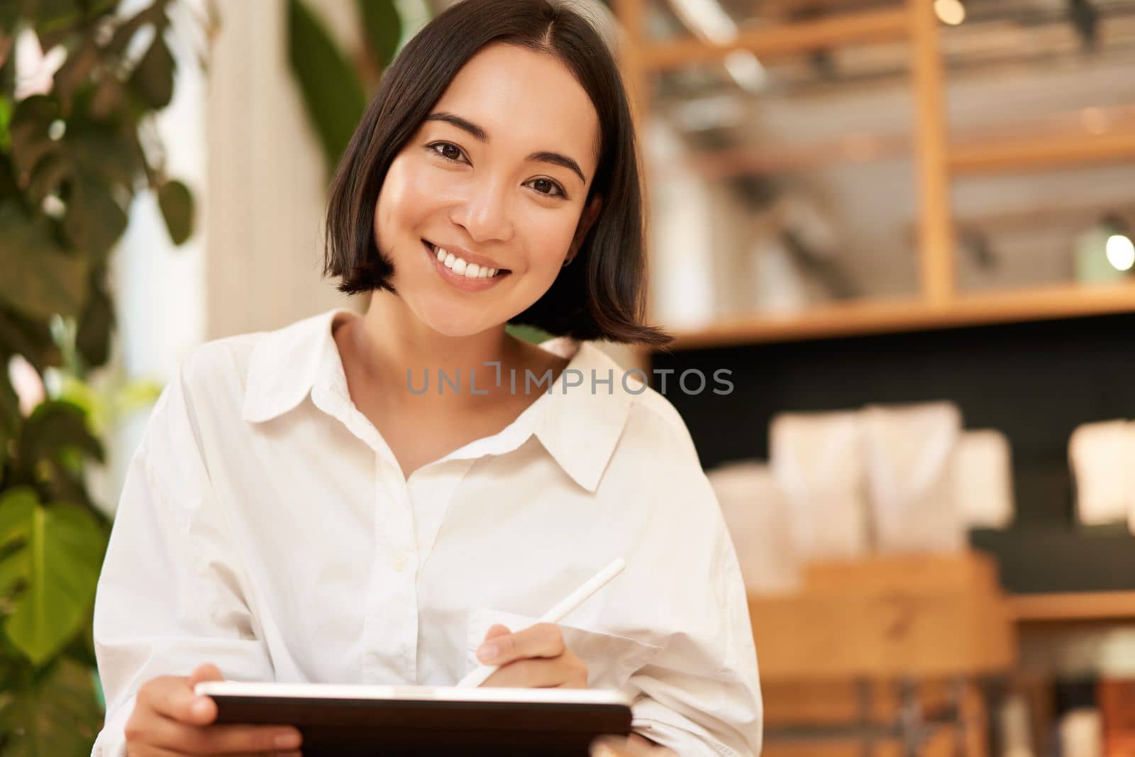 Young beautiful artist, woman drawing on tablet with graphic pen, smiling happily. People and lifestyle concept