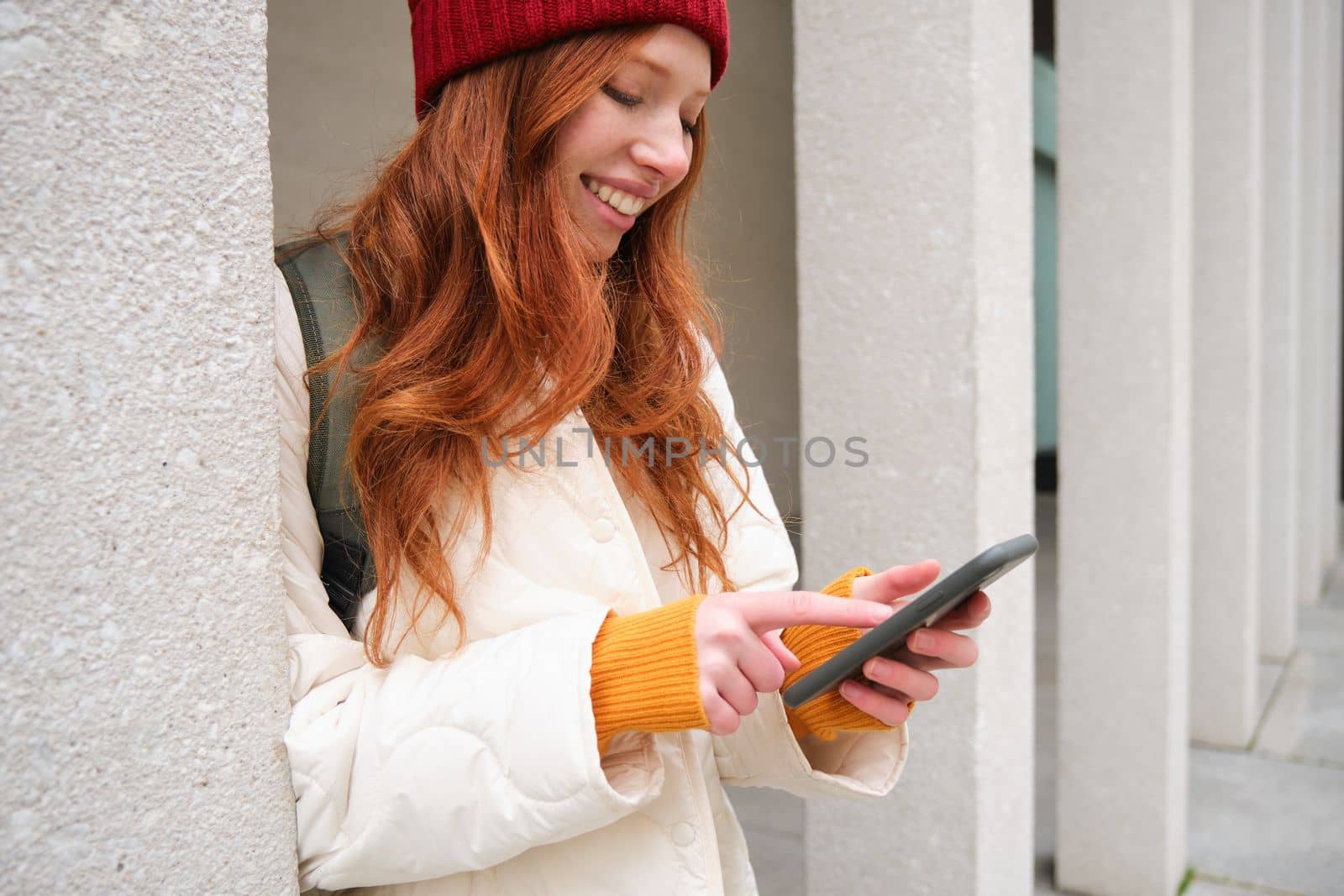 Stylish urban girl using mobile phone app, standing in city, waiting for taxi, looking at smartphone application, texting message by Benzoix