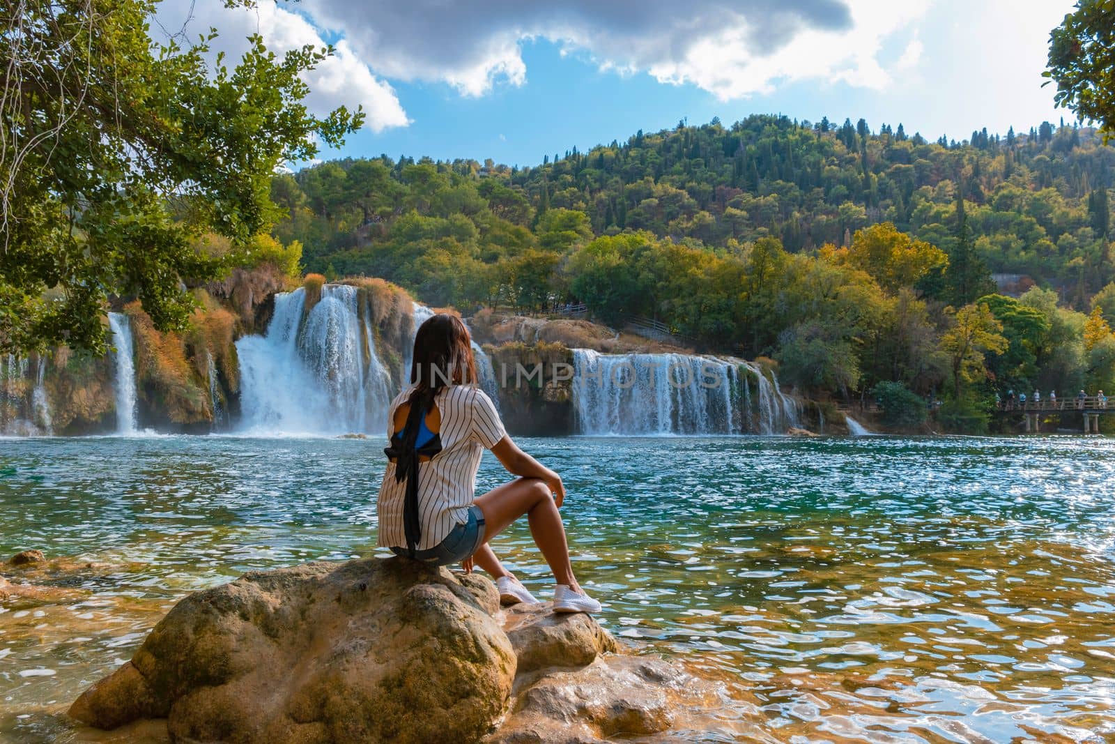 KRKA waterfalls Croatia during summer,young Asian women watching the waterfalls of krka national park Croatia on a bright summer evening in the park by fokkebok
