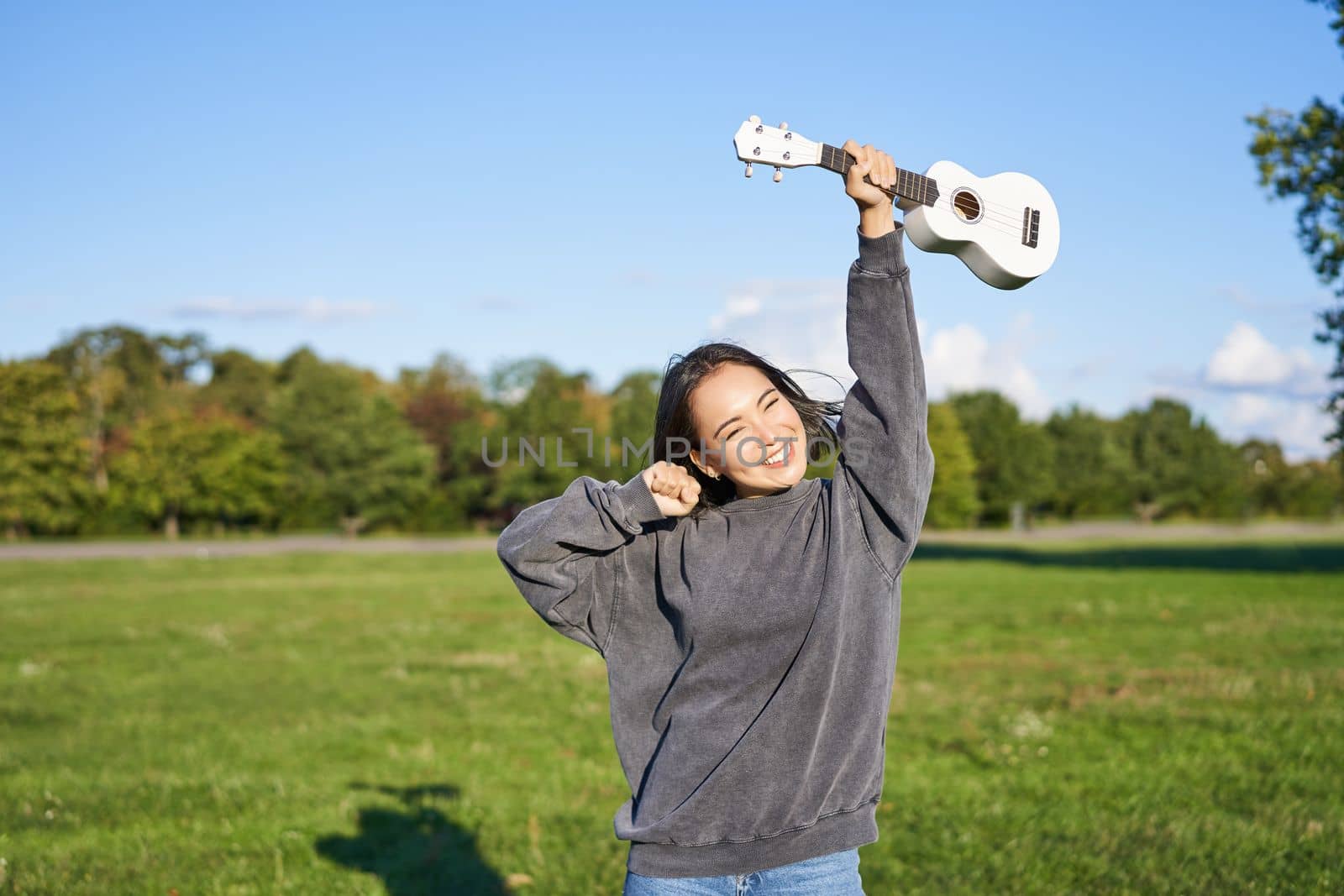 Positive beauty girl with ukulele, dancing and feeling freedom, looking excited, triumphing and celebrating.