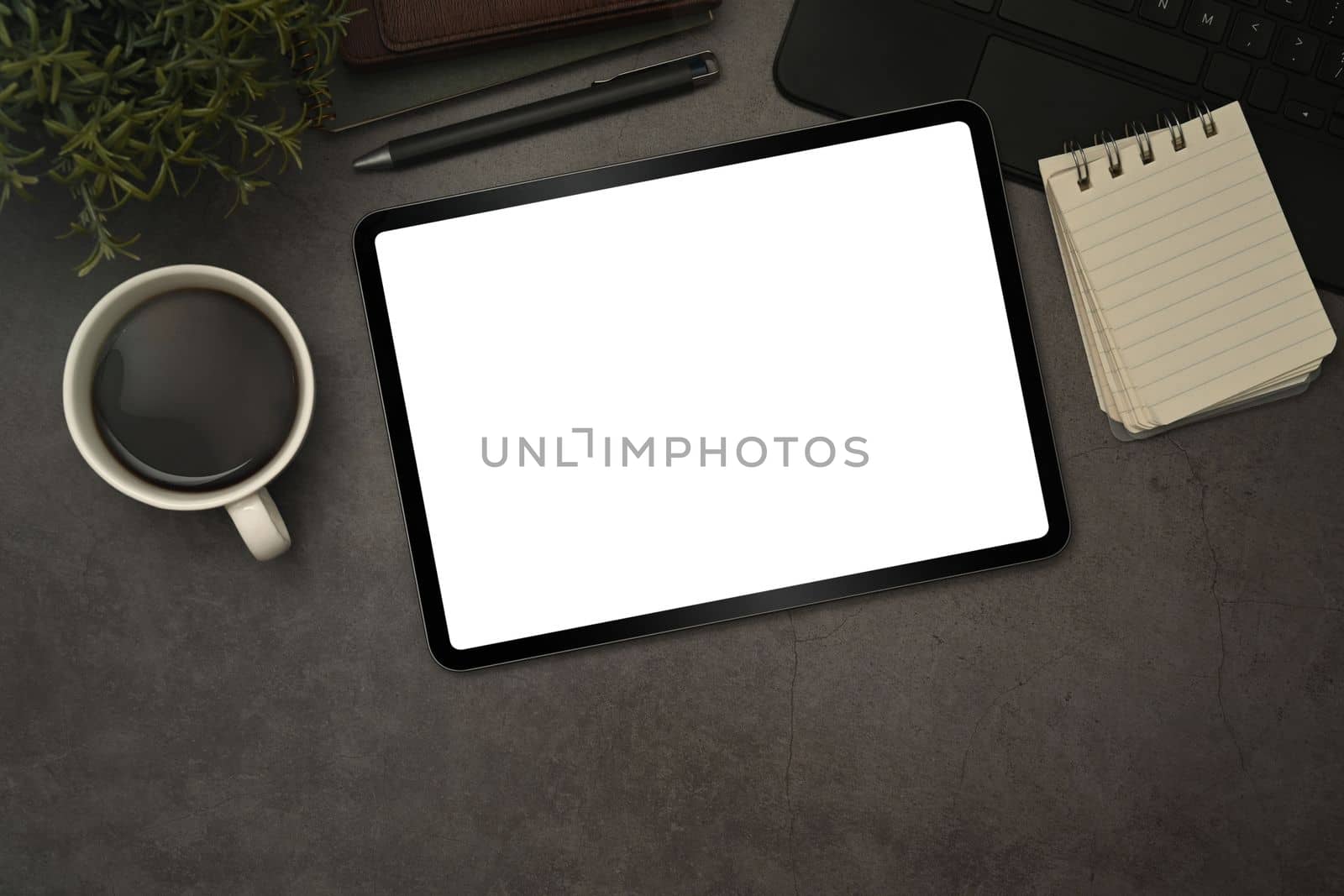 Digital tablet with blank display, cup of coffee and notepad on black slate texture background by prathanchorruangsak