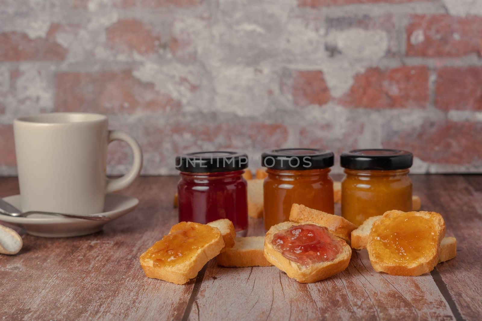 toasted bread with jam and a cup of coffee on a wooden table