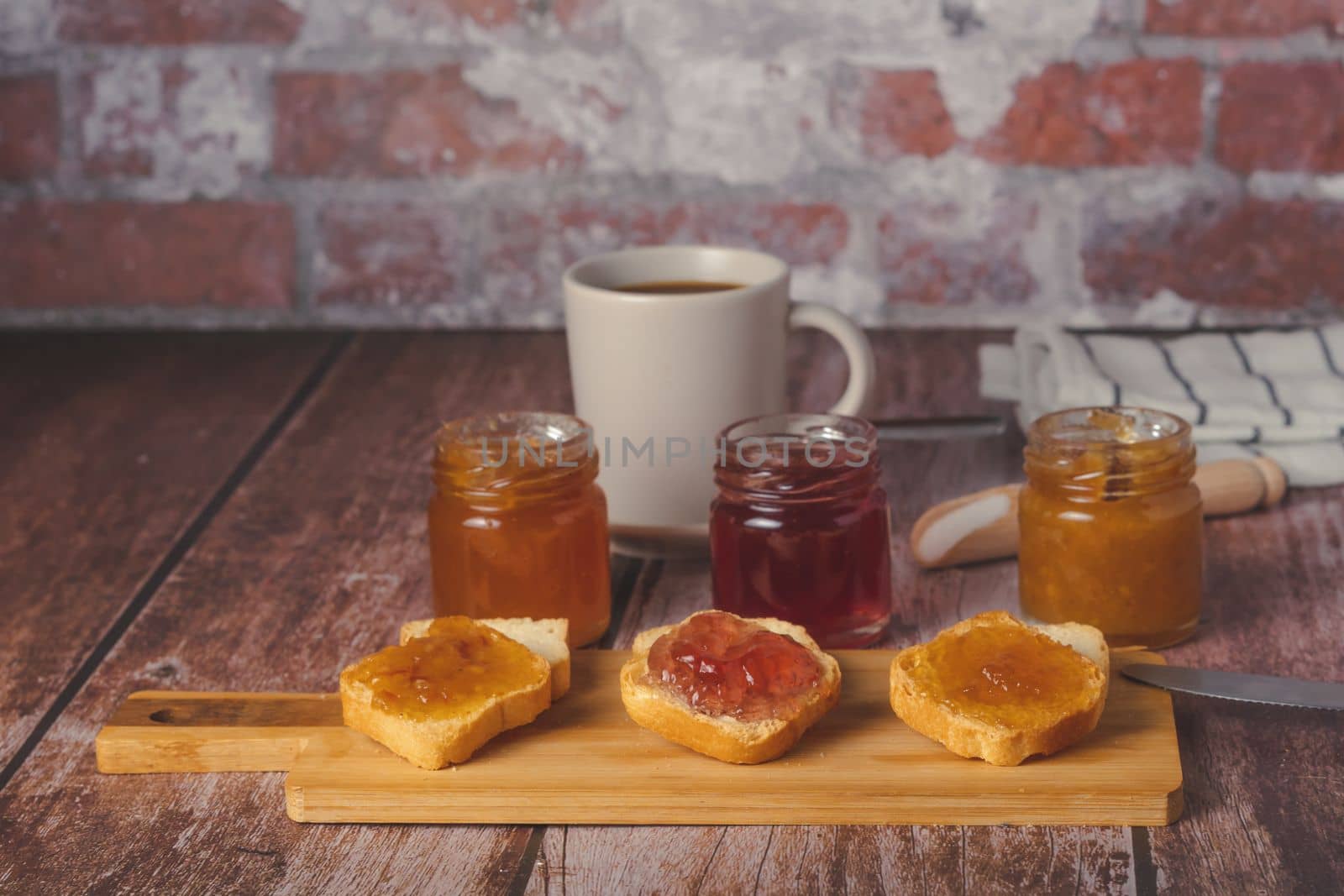small pieces of toast with jam and coffee on a wooden table