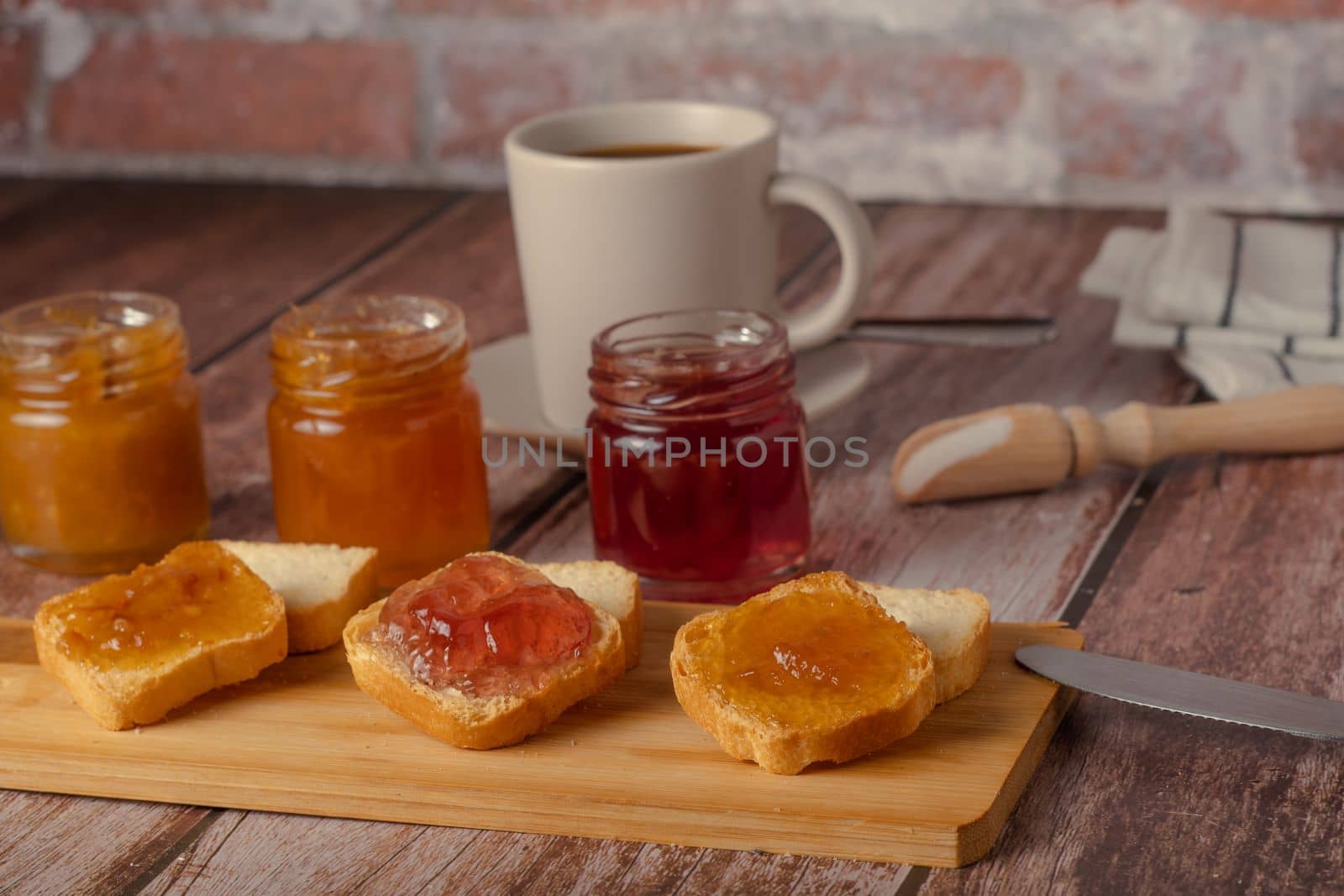 small pieces of toast with jam and coffee on a wooden table