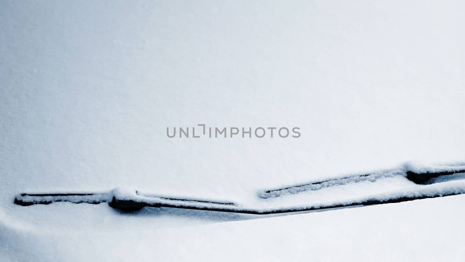 Snowy windshield on a car with wipers. Winter concept for traffic and road safety. by Montypeter