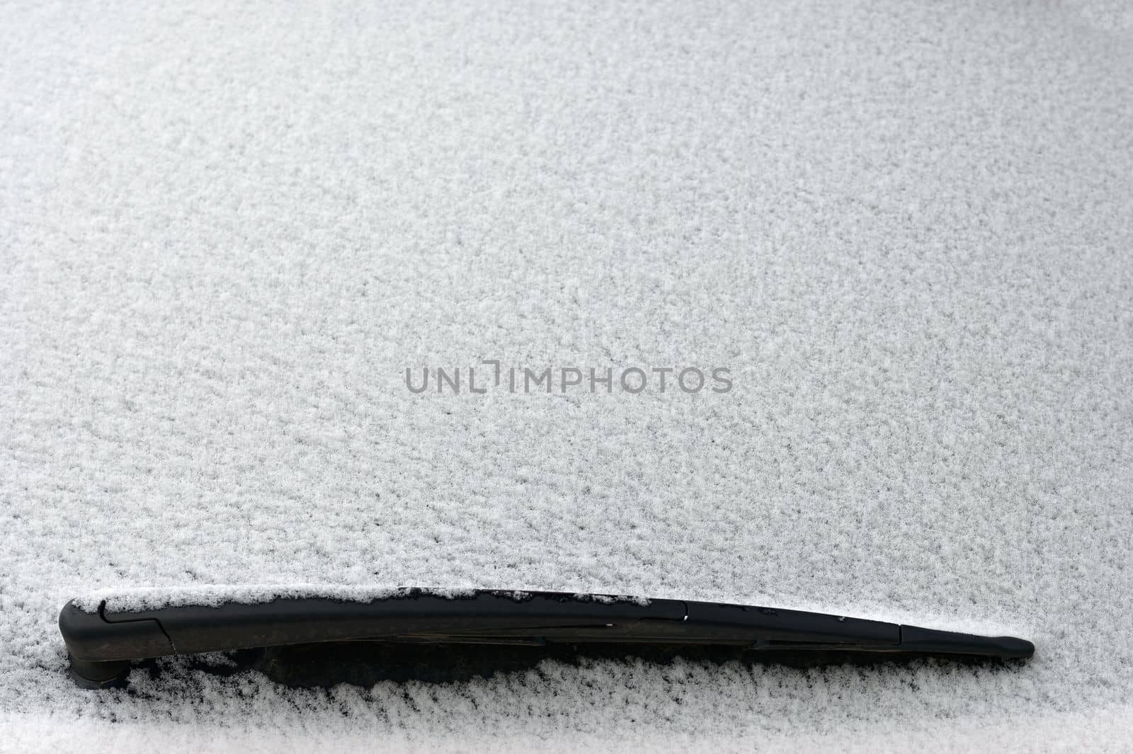 Snowy windshield on a car with wipers. Winter concept for traffic and road safety. by Montypeter