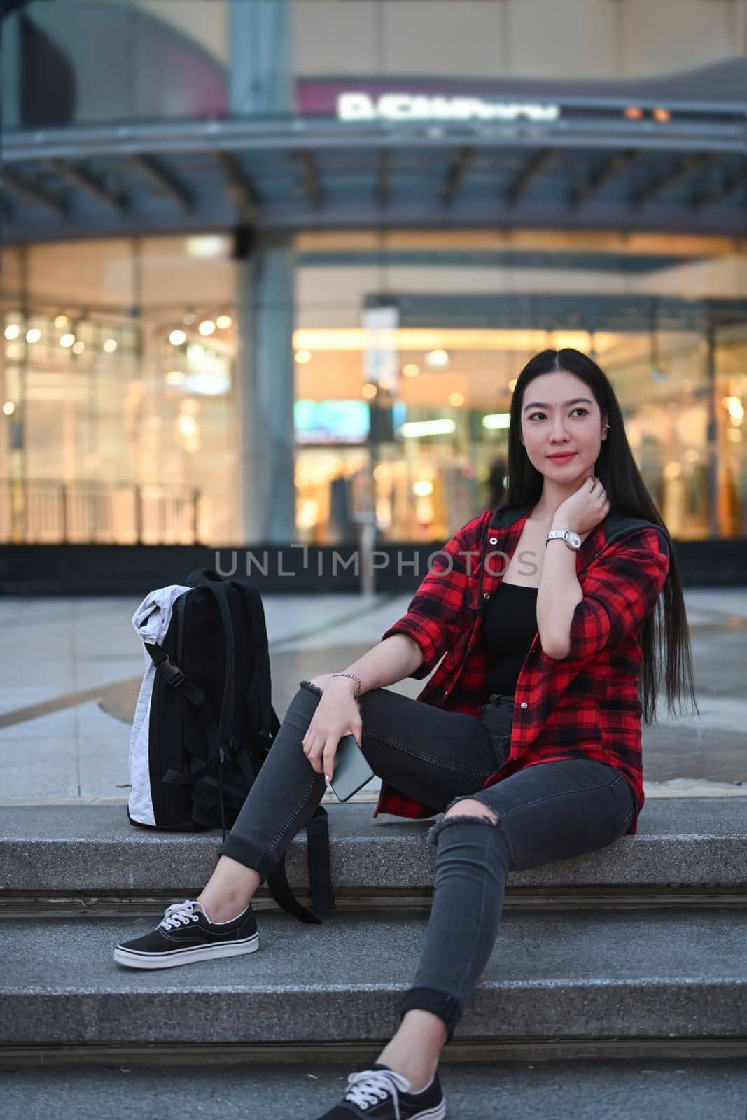 Full length portrait of smiling woman Asian woman sitting on stairs in city at night.