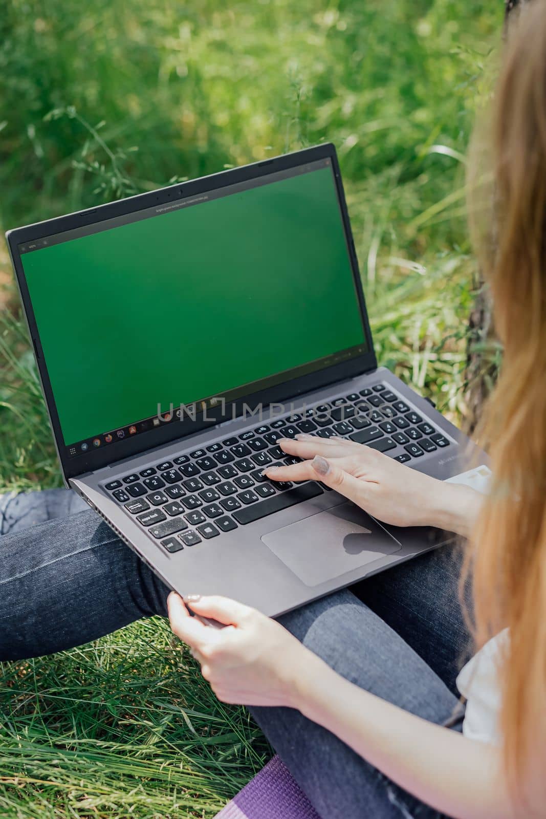 girl sits on the grass and works at a laptop. freelance. selfeducation. the concept of distance learning outdoors