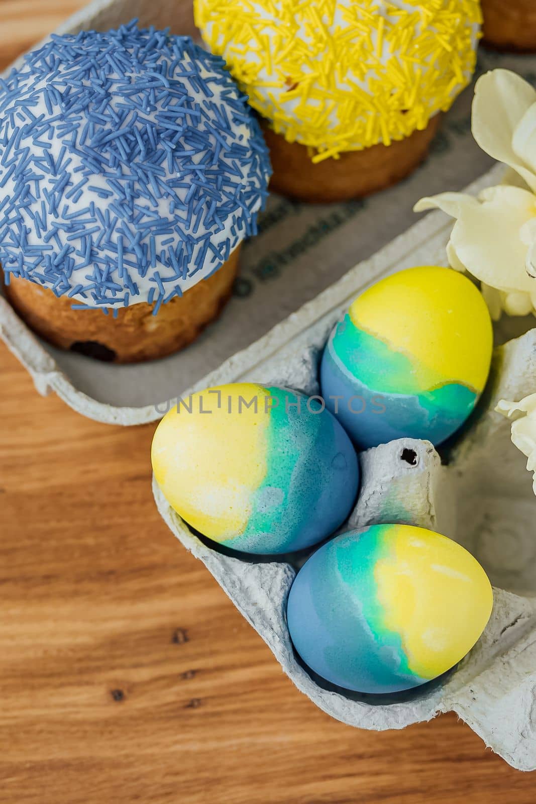 Easter cakes in the colors of the flag of Ukraine, yellow and blue in a cardboard stand with eggs, Easter eggs. place for text. selective focus.