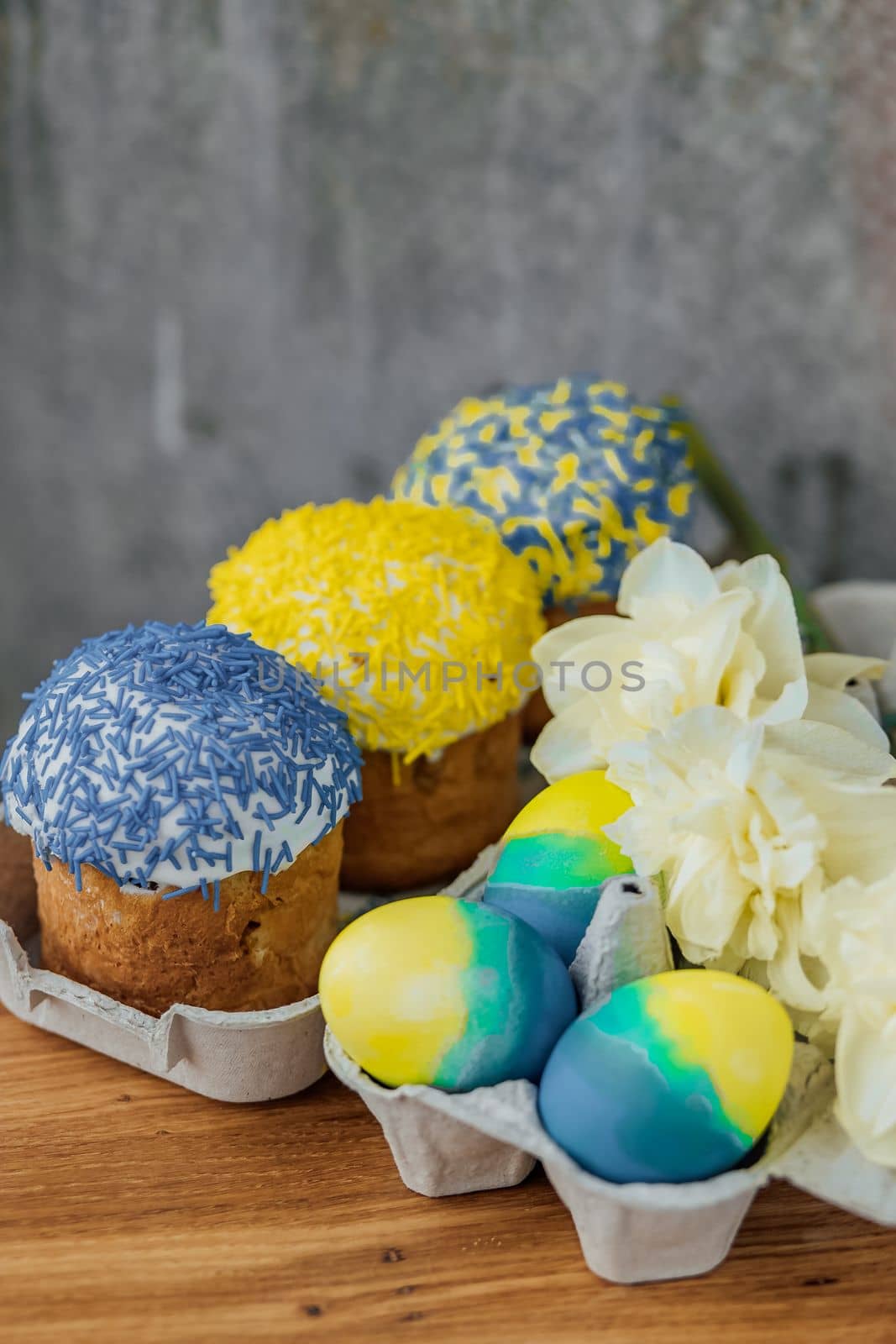 Easter cakes in the colors of the flag of Ukraine, yellow and blue in a cardboard stand with eggs, Easter eggs. place for text. selective focus.