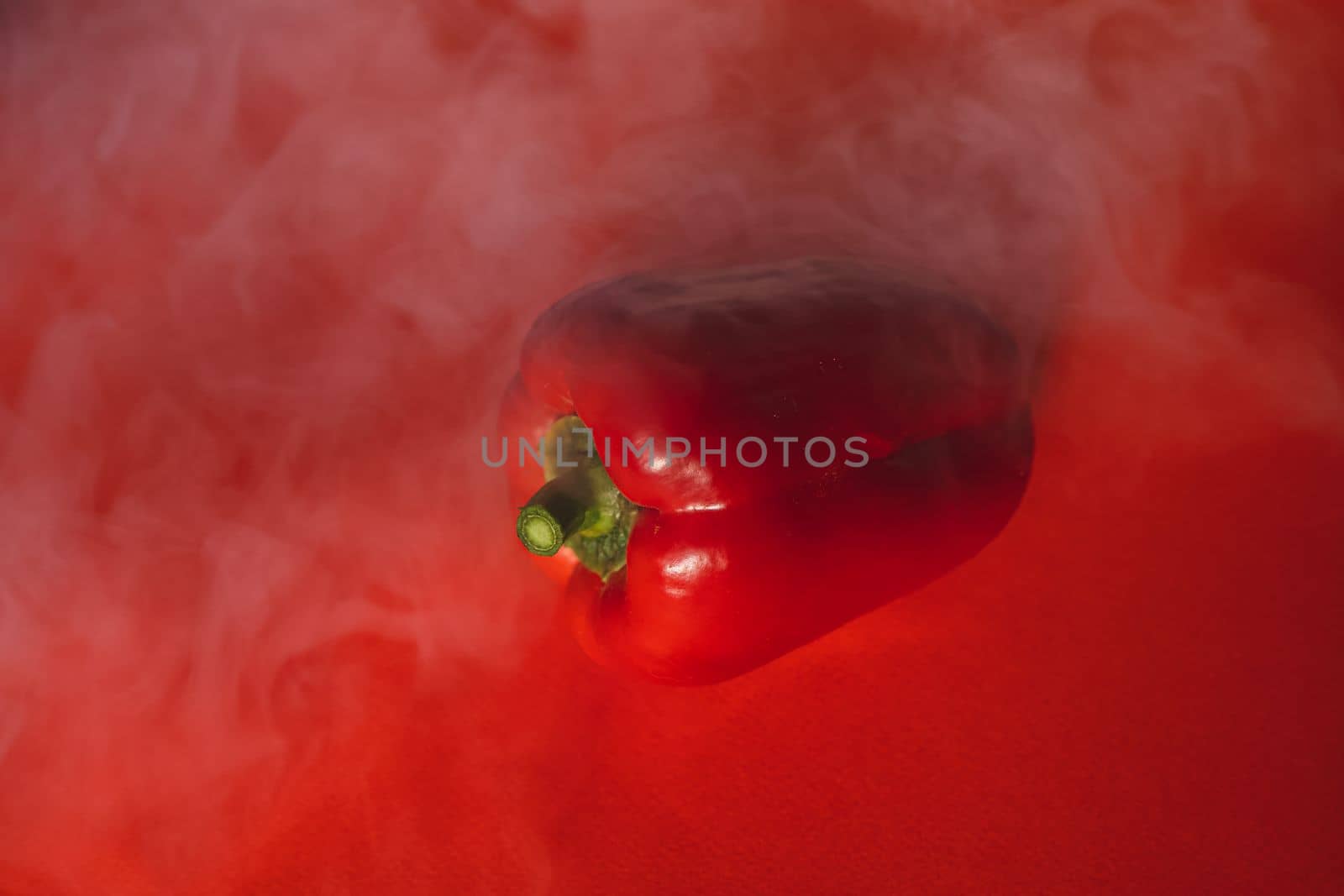 SWEET, fresh RED PEPPER ON A RED BACKGROUND WITH A LIGHT SMOKE.