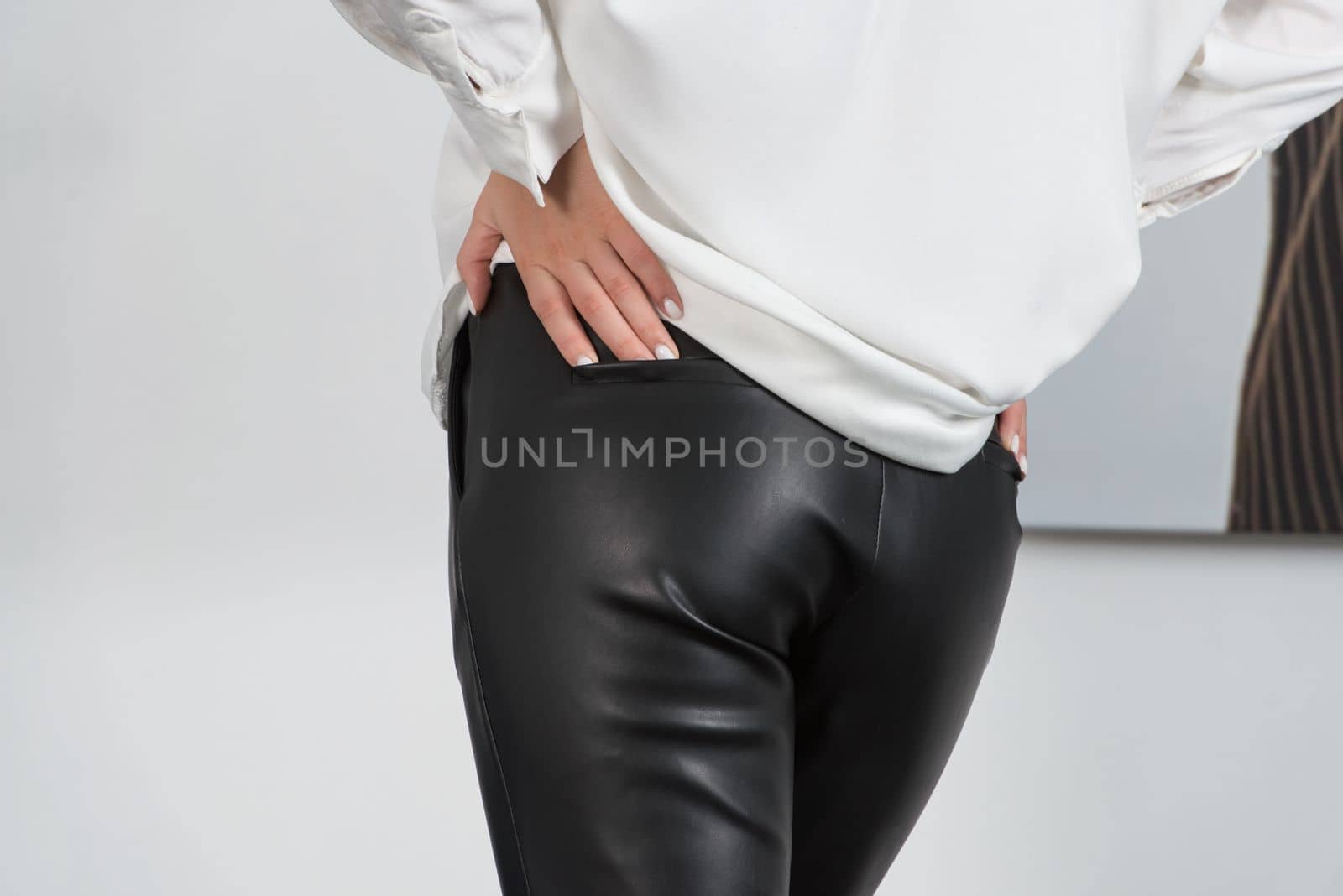 Stylish beautiful young blond woman in a tight black pants and white shirt near a white wall in the room. Attractive girl model posing. by Ashtray25