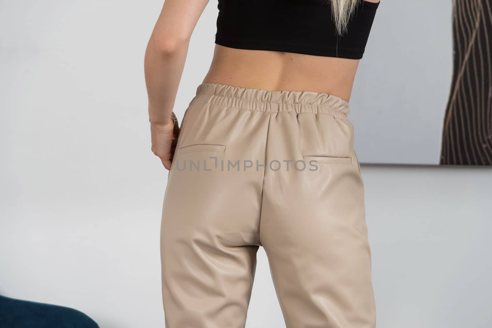 Stylish beautiful young blond woman in a tight biege pants, black top and white shirt near a white wall in the room. Attractive girl model posing. by Ashtray25