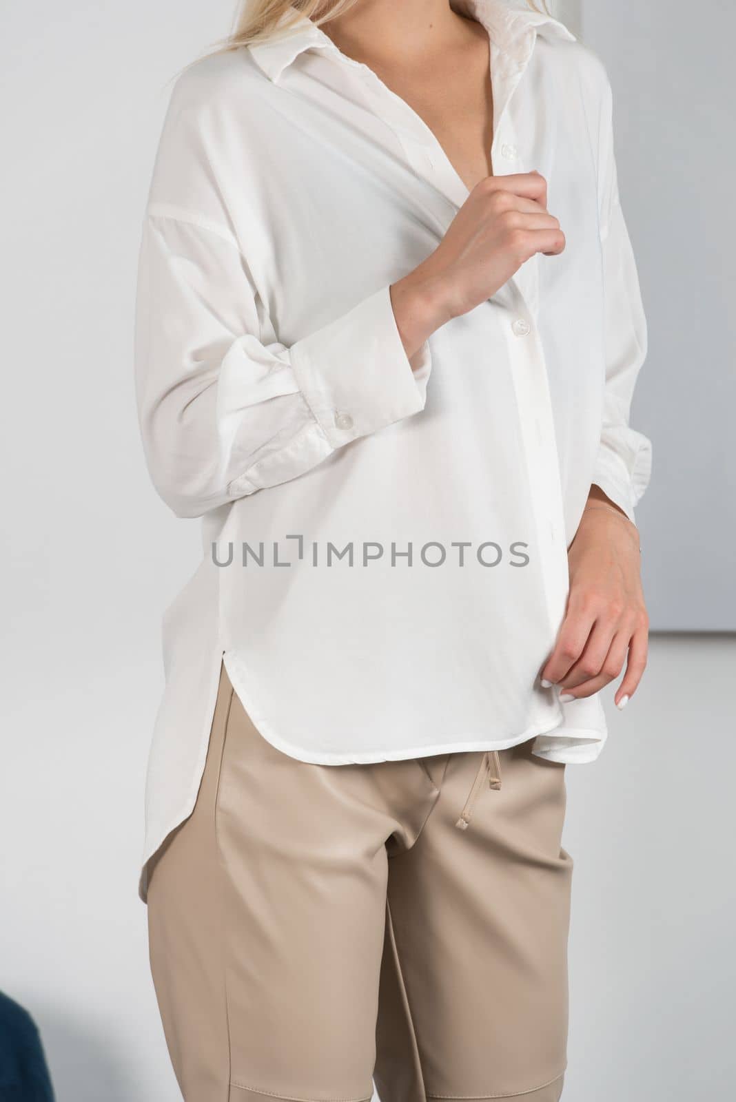 Stylish beautiful young blond woman in a tight biege pants and white shirt near a white wall in the room. Attractive girl model posing. by Ashtray25