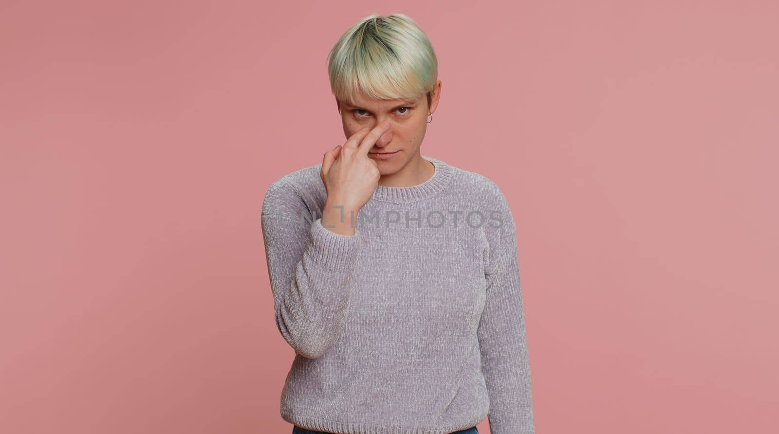 I am watching you. Caucasian woman with short hair pointing at her eyes and camera, show I am watching you gesture, spying on someone. Young girl on pink studio background. Lgbt gay lesbian people