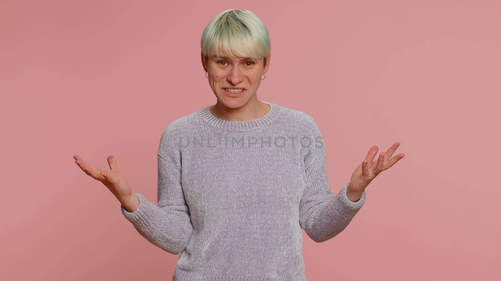 What Why. Sincere irritated woman raising hands in indignant expression asking reason of failure demonstrating disbelief irritation by troubles. Confused one girl on pink background. Lgbt gay lesbian