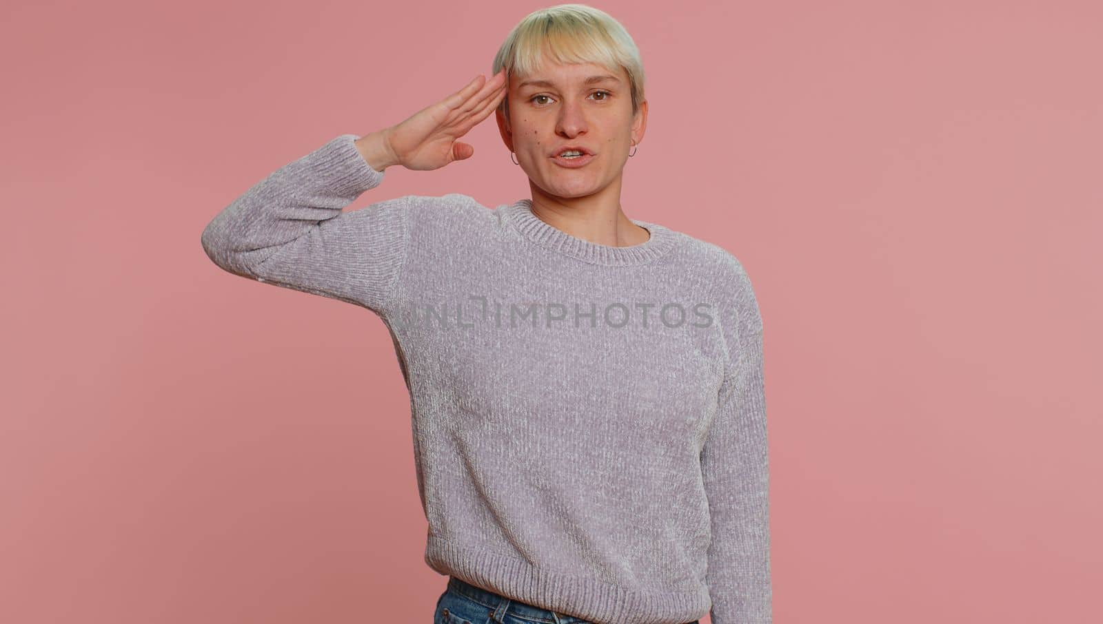 Yes sir. Subordinate responsible serious woman giving salute listening to order as if soldier following discipline obeying expressing confidence. Young girl on pink background. Lgbt gay lesbian people