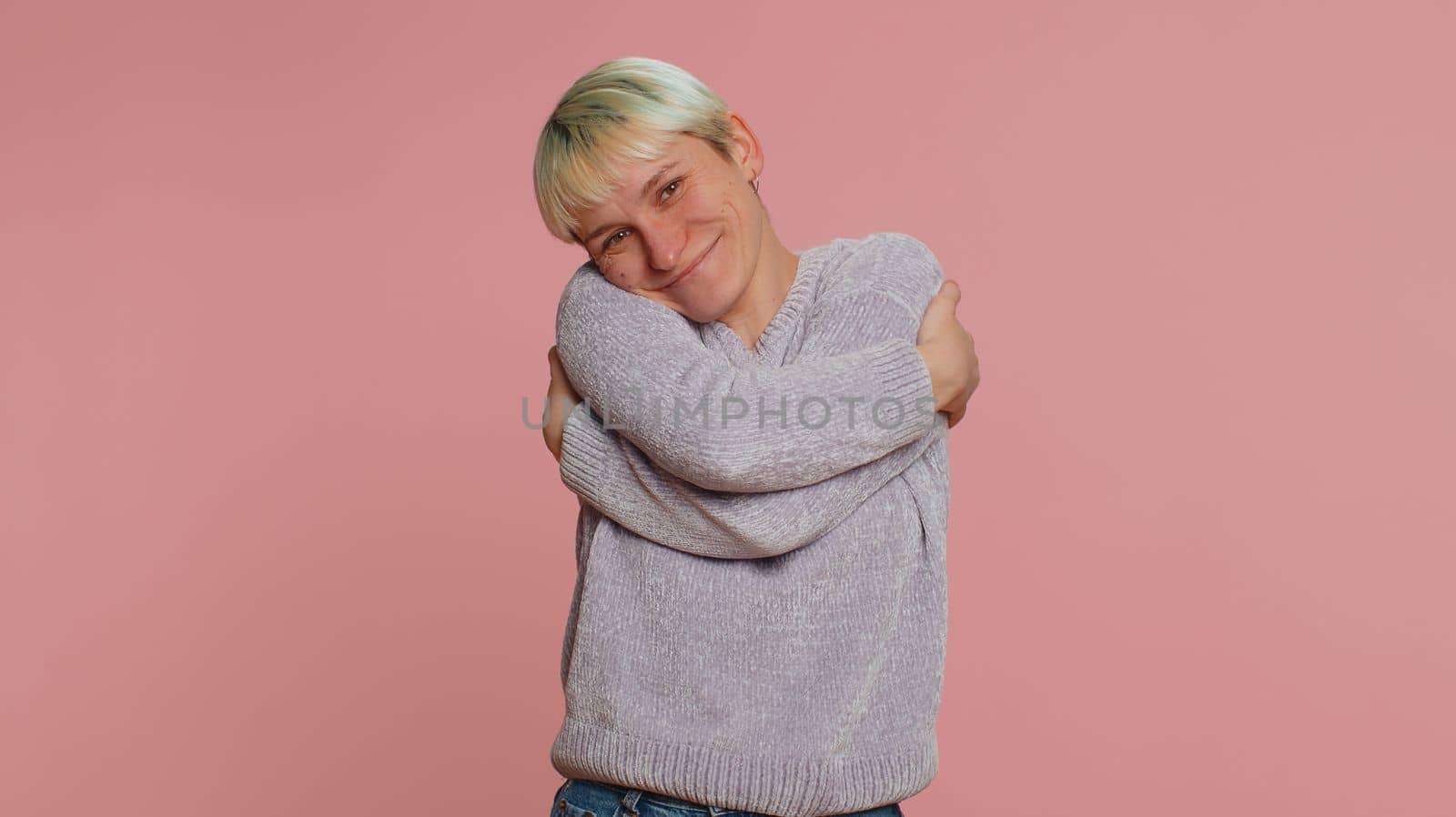 Come to me, I want to embrace you. Woman with short hair spread hands and give hug to you. Pleasant expression, love feelings. Young girl isolated on pink studio background. Lgbt gay lesbian people