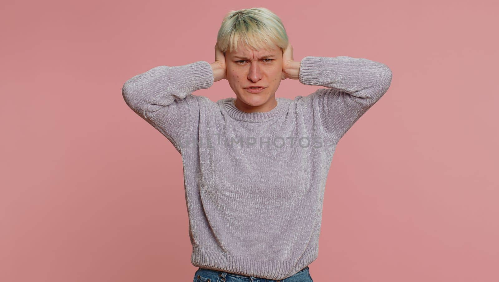 Dont want to hear and listen. Frustrated annoyed irritated woman covering ears, gesturing No, avoiding advice ignoring unpleasant noise loud voices. Girl on pink background. Lgbt gay lesbian people