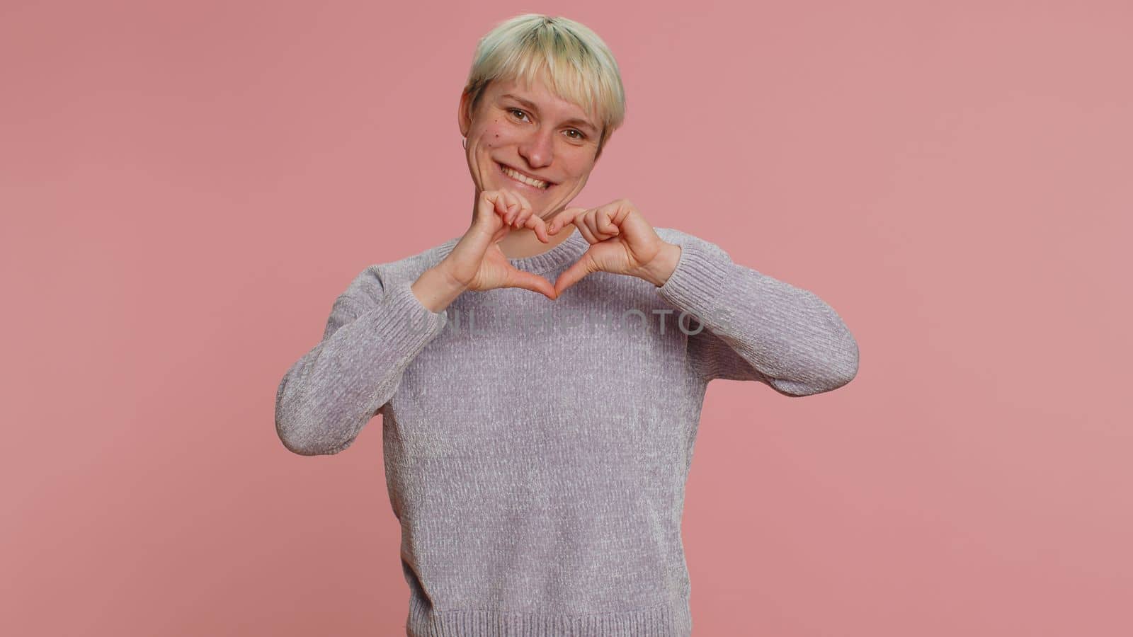 Smiling pretty woman makes heart gesture demonstrates love sign expresses good feelings and sympathy by efuror